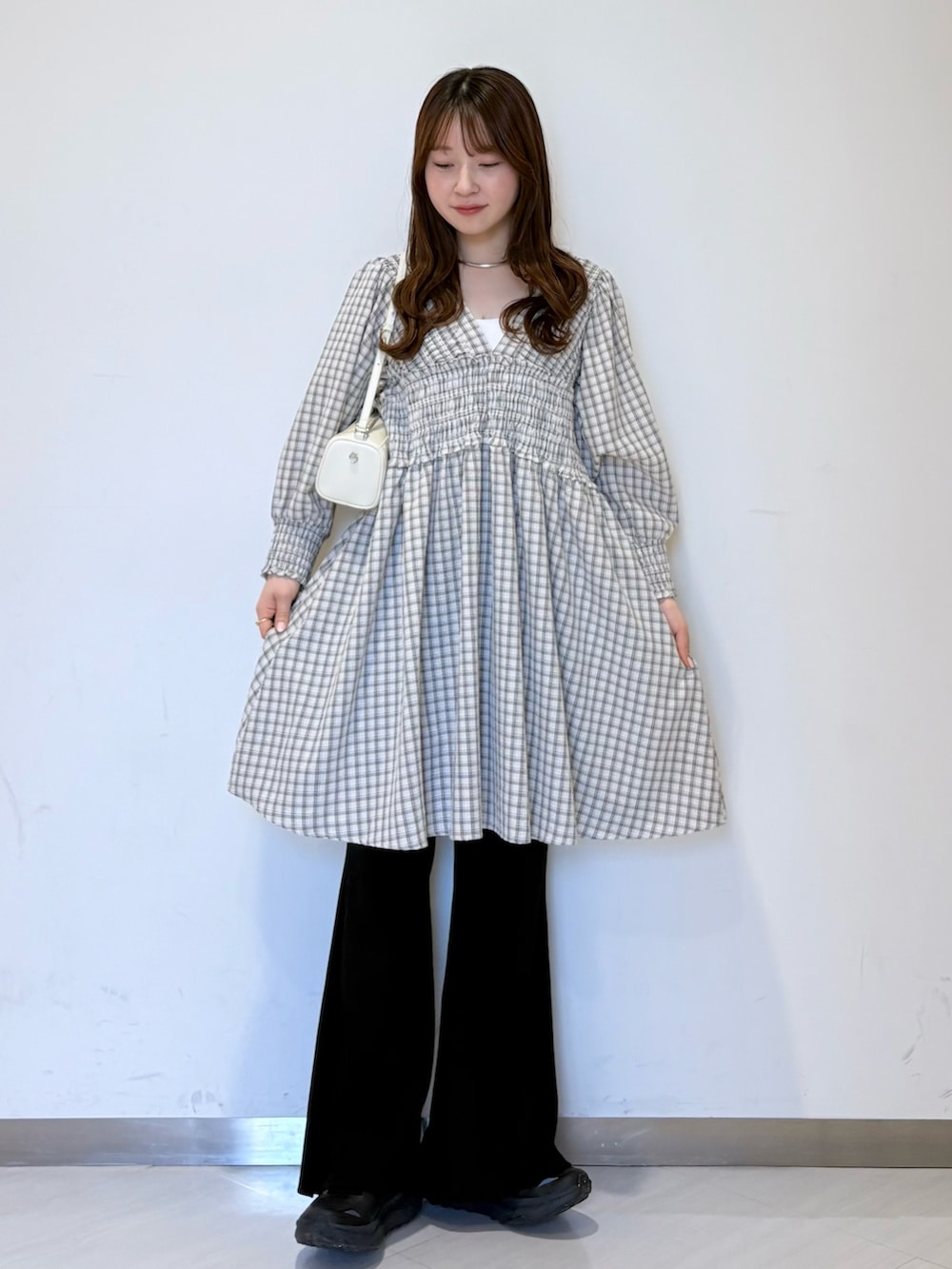 ブラック系のその他パンツ、ベージュ系のワンピース、ホワイト系のショルダーバッグを着用したレディースの春コーディネートの2枚目の写真