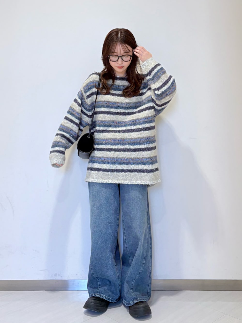 ブルー系のニット/セーター、ブルー系のデニムパンツ、ブラック系のショルダーバッグを着用したレディースの秋コーディネートの3枚目の写真