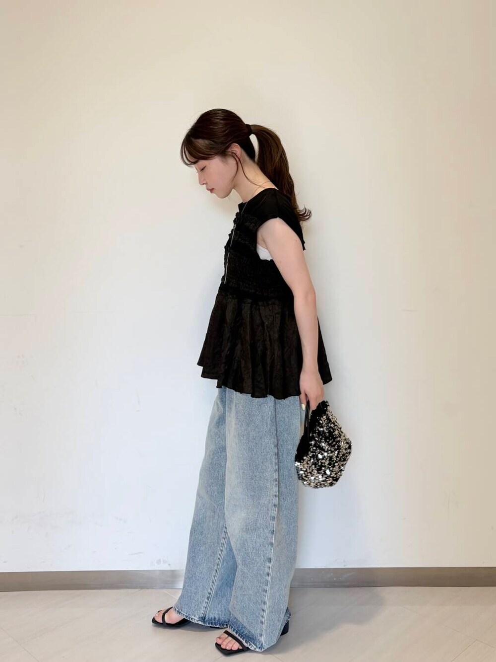ブルー系のデニムパンツ、シルバー系のショルダーバッグ、ブルー系のサンダルを着用したレディースの夏コーディネートの3枚目の写真