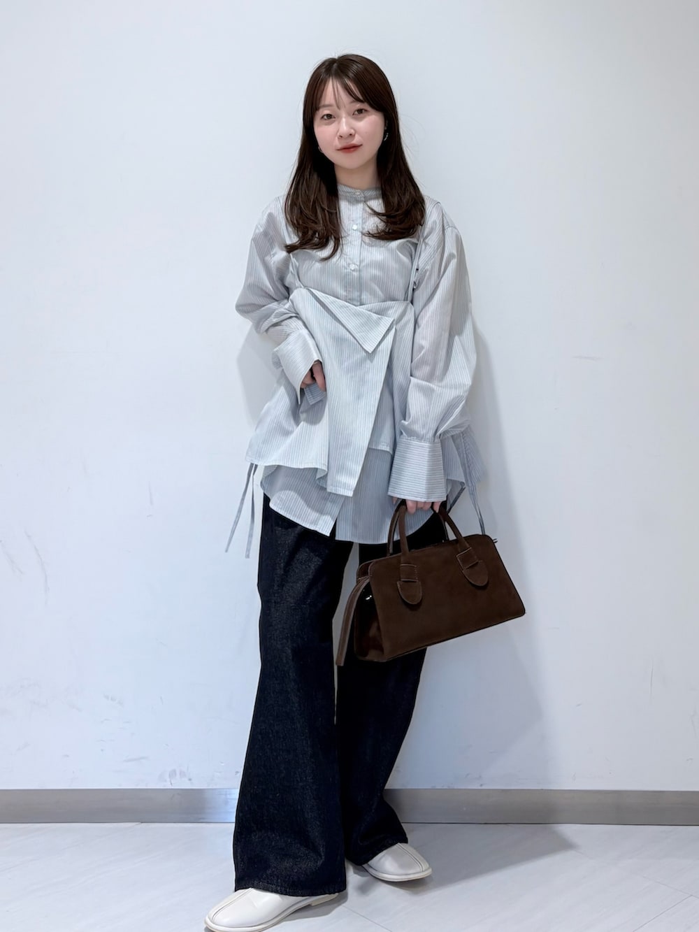 グレー系のシャツ/ブラウス、ホワイト系のパンプス、ブラウン系のボストンバッグを着用したレディースの冬コーディネートの3枚目の写真