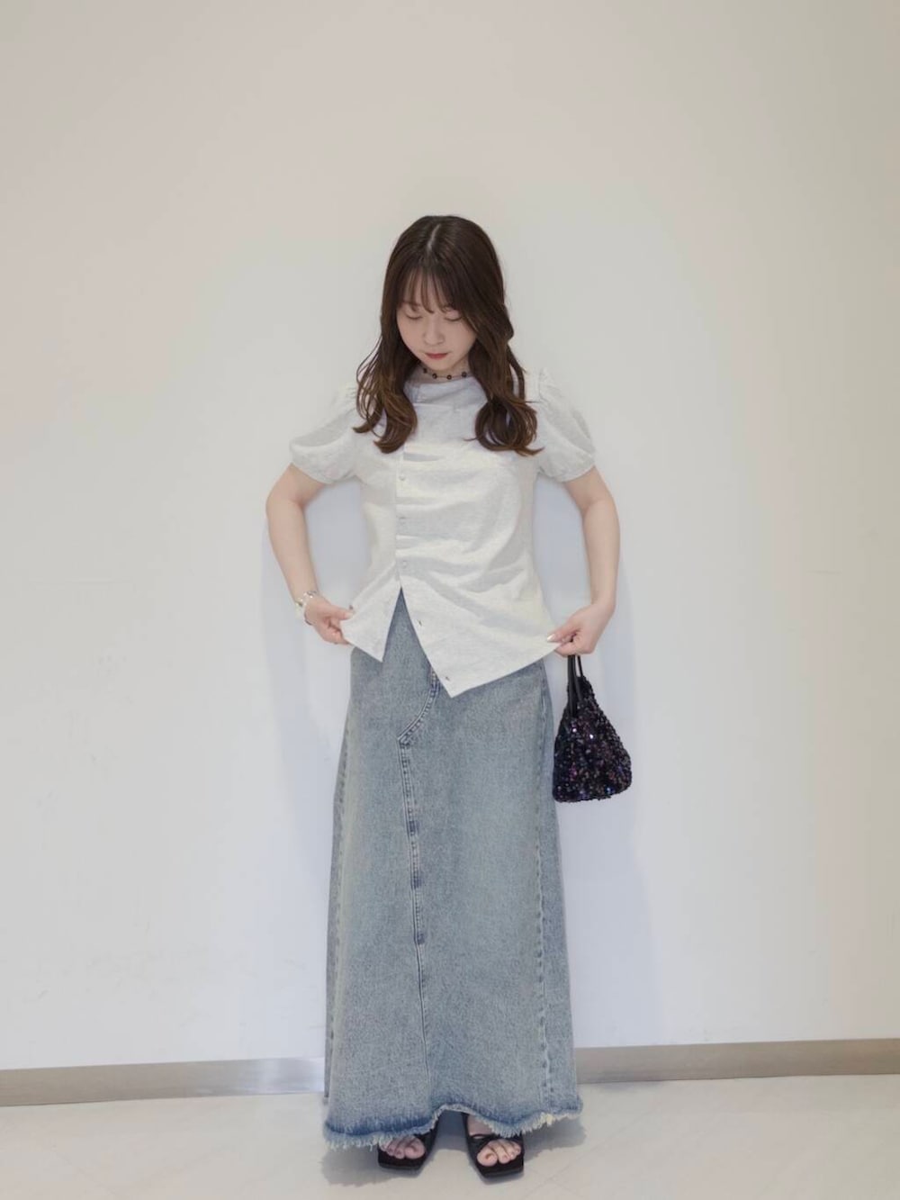 ブラック系のショルダーバッグ、ブラック系のサンダル、ブルー系のスカートを着用したレディースの春コーディネートの2枚目の写真