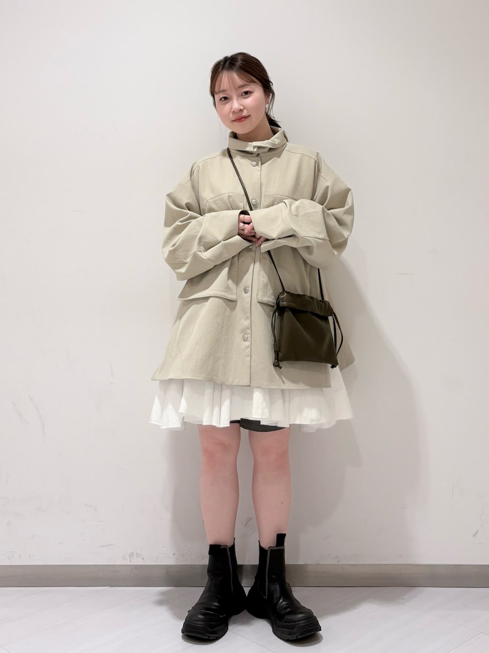 グリーン系のショルダーバッグ、ベージュ系のその他アウター、ホワイト系のワンピースを着用したレディースの春コーディネートの4枚目の写真