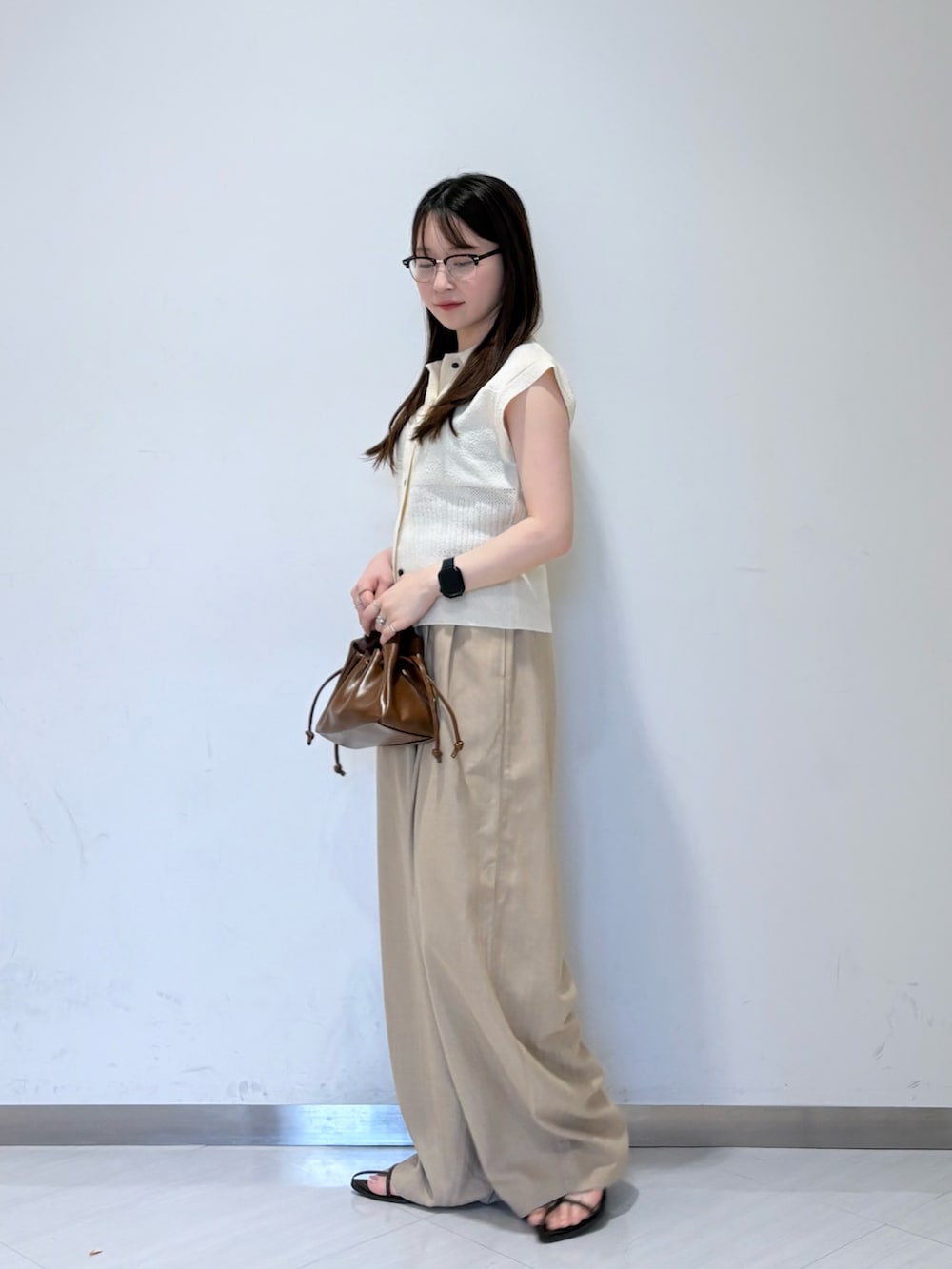ホワイト系のニット/セーター、ベージュ系のその他パンツ、ブラウン系のハンドバッグを着用したレディースの夏コーディネートの2枚目の写真