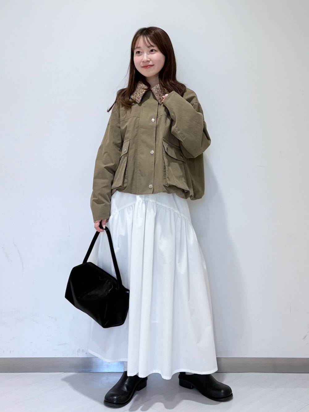 グリーン系のブルゾン、ブラック系のその他シューズ、ホワイト系のスカートを着用したレディースの春コーディネートの4枚目の写真