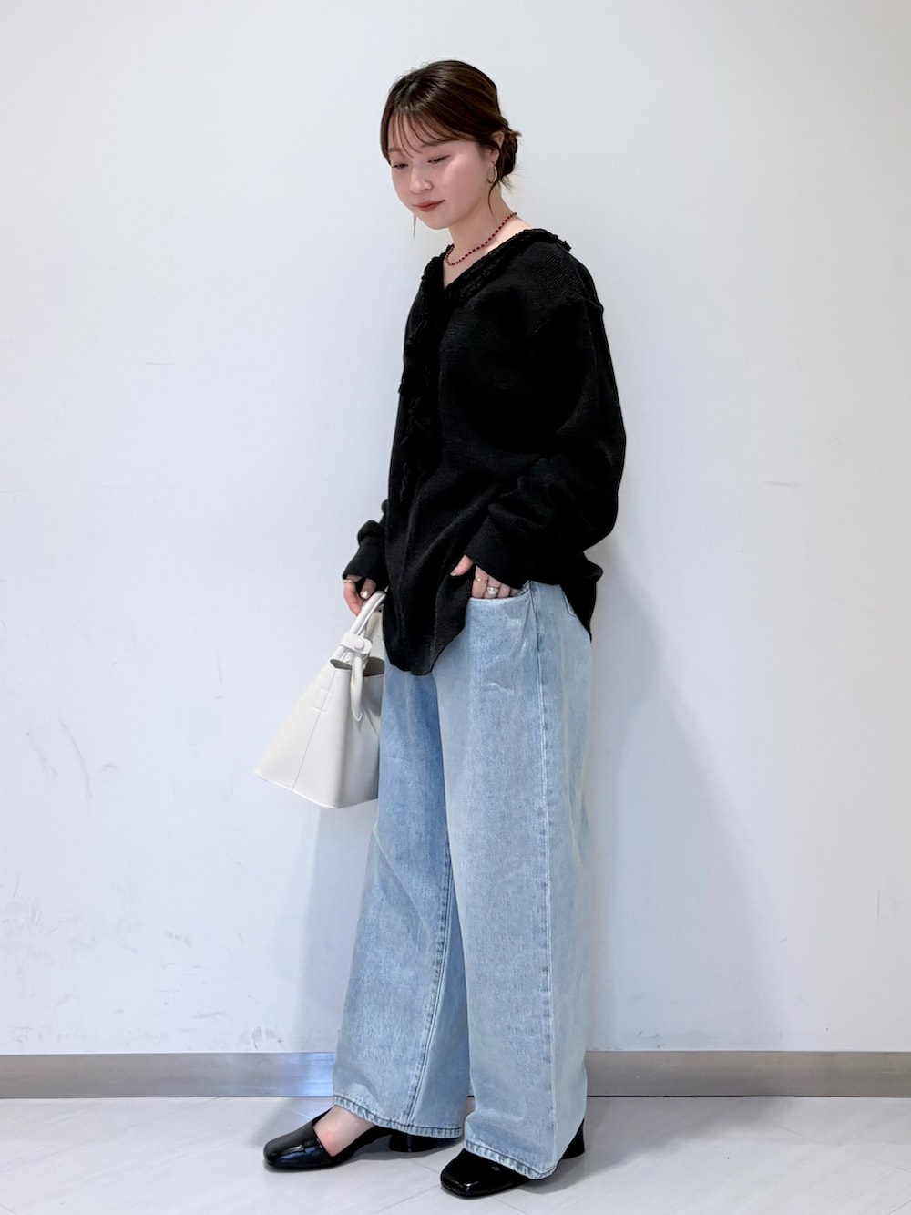 ブラック系のパンプス、ホワイト系のハンドバッグ、ブルー系のデニムパンツを着用したレディースの春コーディネートの2枚目の写真