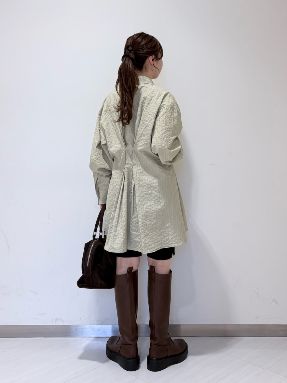 グリーン系のワンピース、ブラウン系のブーツ、ブラック系のその他パンツを着用したレディースの冬コーディネートの3枚目の写真