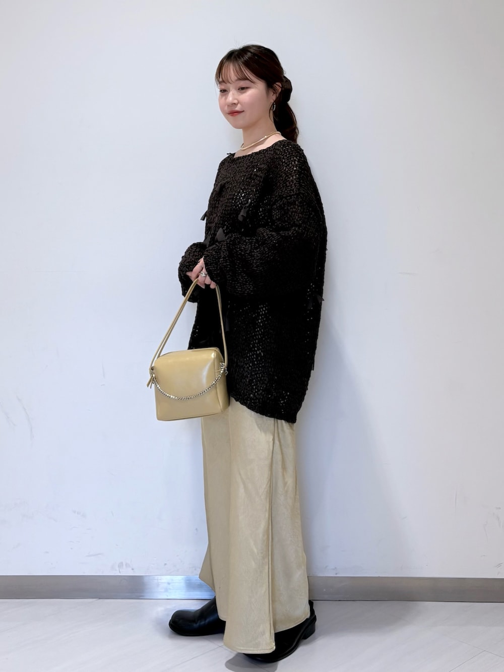 ベージュ系のスカート、ブラウン系のニット/セーター、ベージュ系のショルダーバッグを着用したレディースの冬コーディネートの2枚目の写真