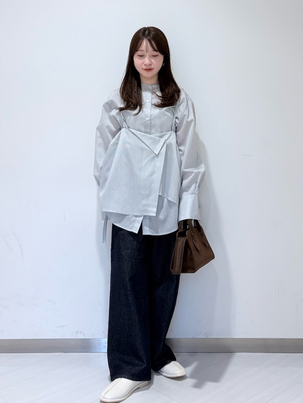 グレー系のシャツ/ブラウス、ホワイト系のパンプス、ブラウン系のボストンバッグを着用したレディースの冬コーディネートの2枚目の写真