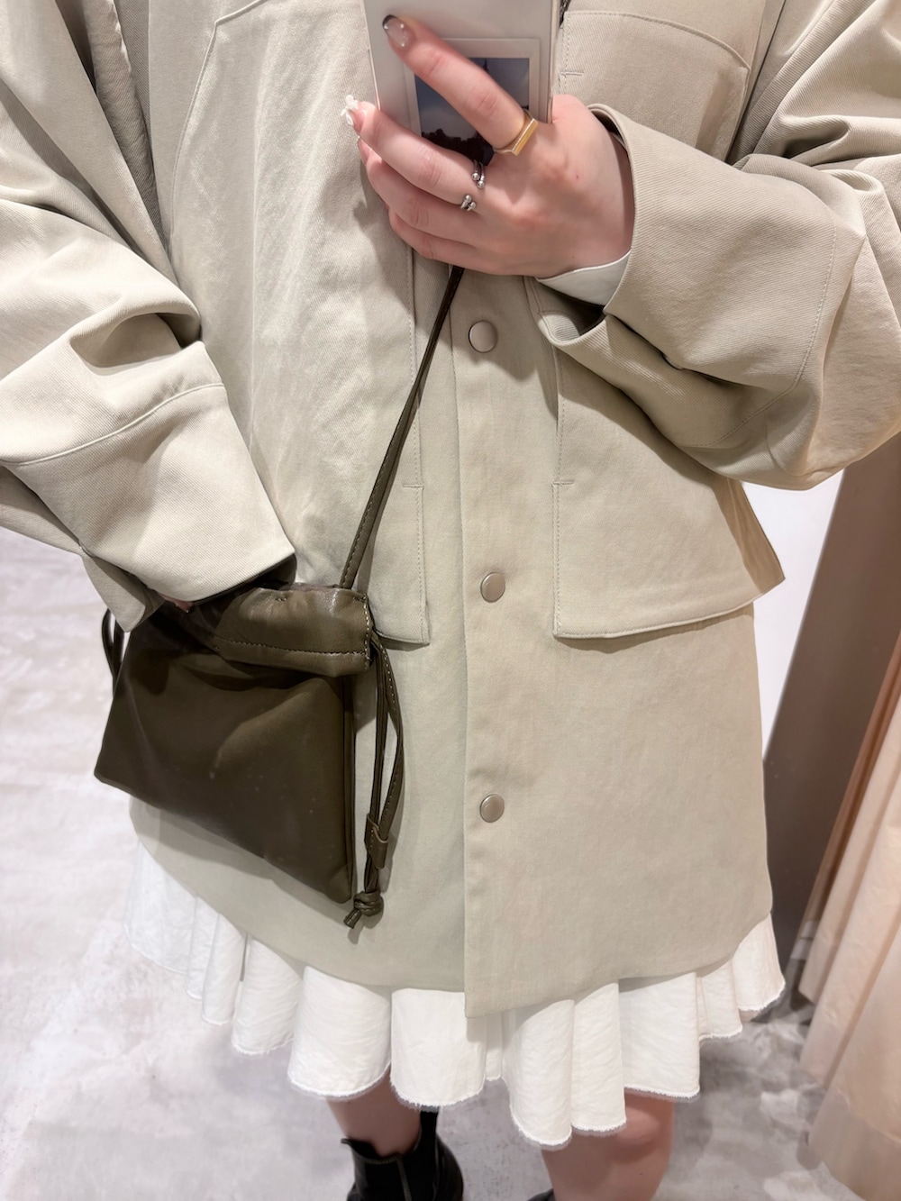 グリーン系のショルダーバッグ、ベージュ系のその他アウター、ホワイト系のワンピースを着用したレディースの春コーディネートの5枚目の写真