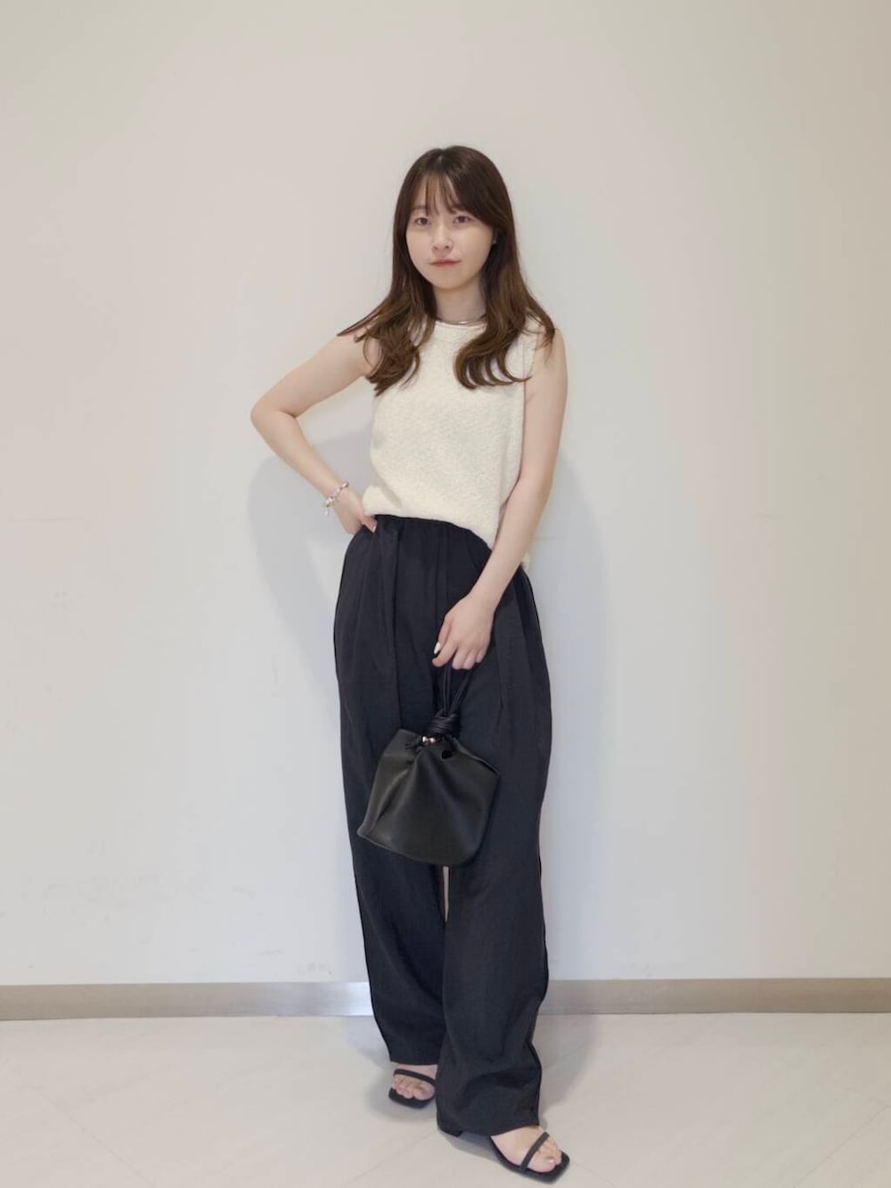 ブラック系のショルダーバッグ、ブルー系のサンダル、ホワイト系のニット/セーターを着用したレディースの夏コーディネートの2枚目の写真