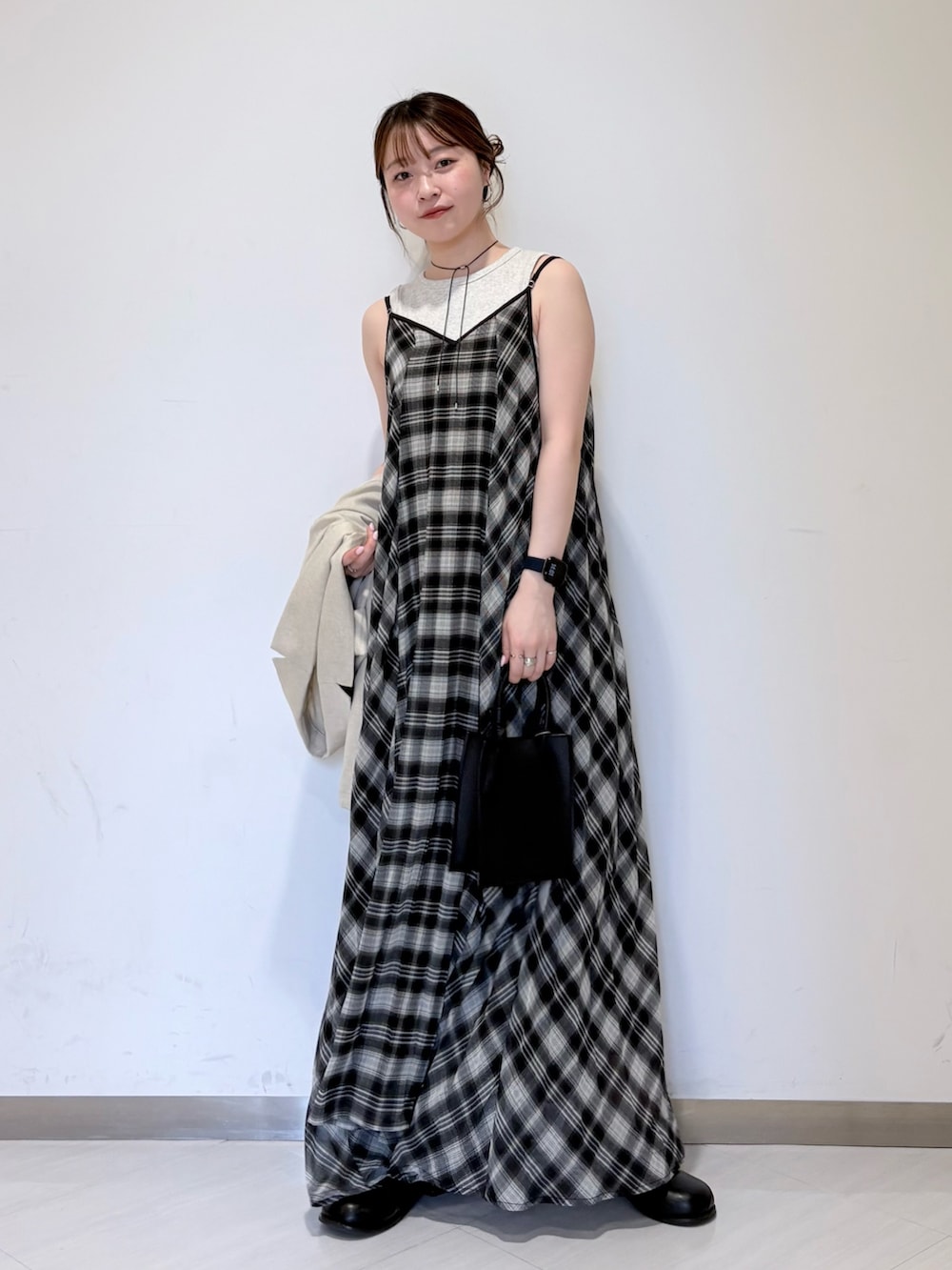 ベージュ系のタンクトップ、ブラック系のワンピース、ブラック系のハンドバッグを着用したレディースの春コーディネートの4枚目の写真