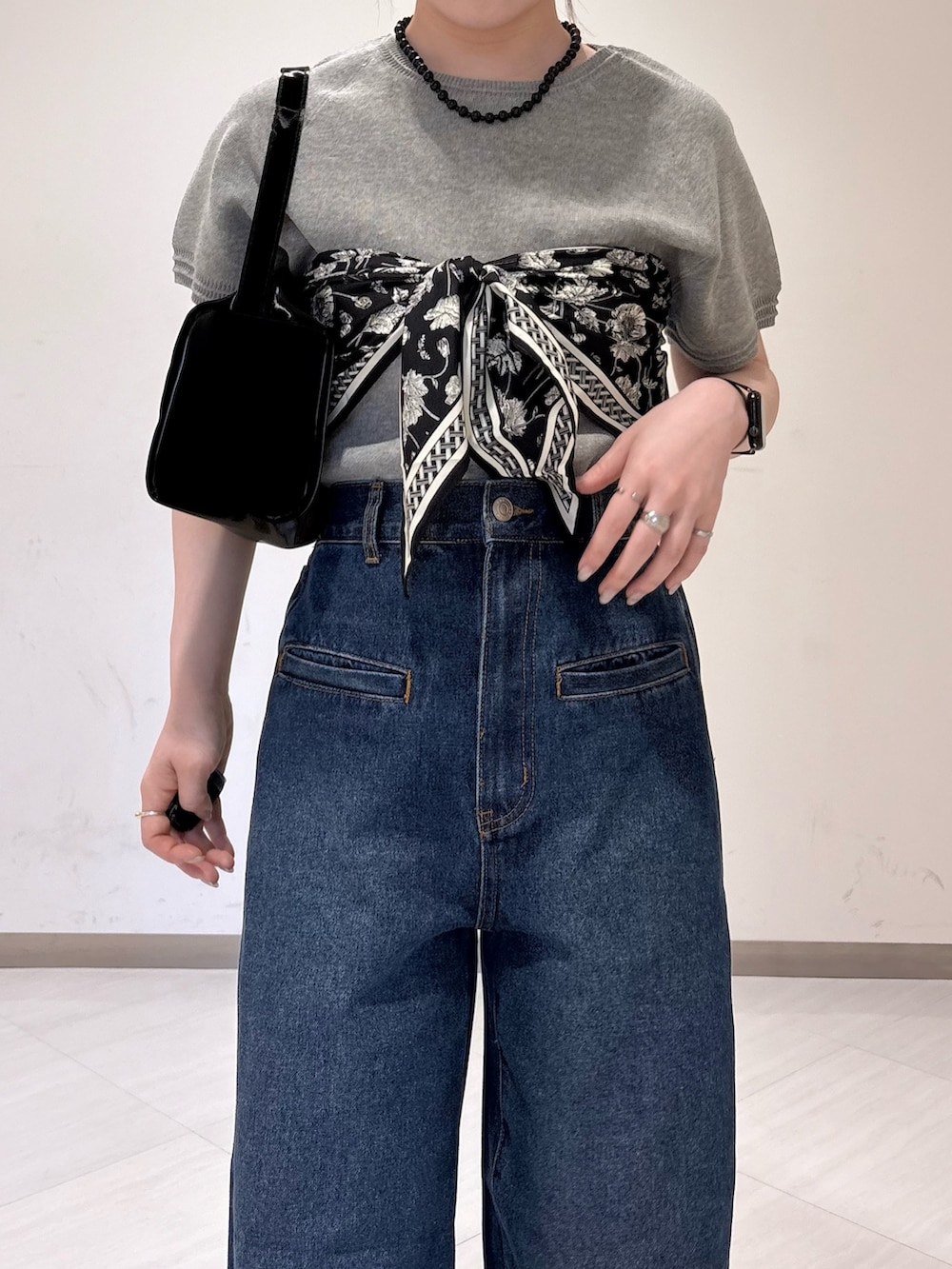 グレー系のニット/セーター、ブルー系のデニムパンツ、ブラック系のトートバッグを着用したレディースの春コーディネートの5枚目の写真