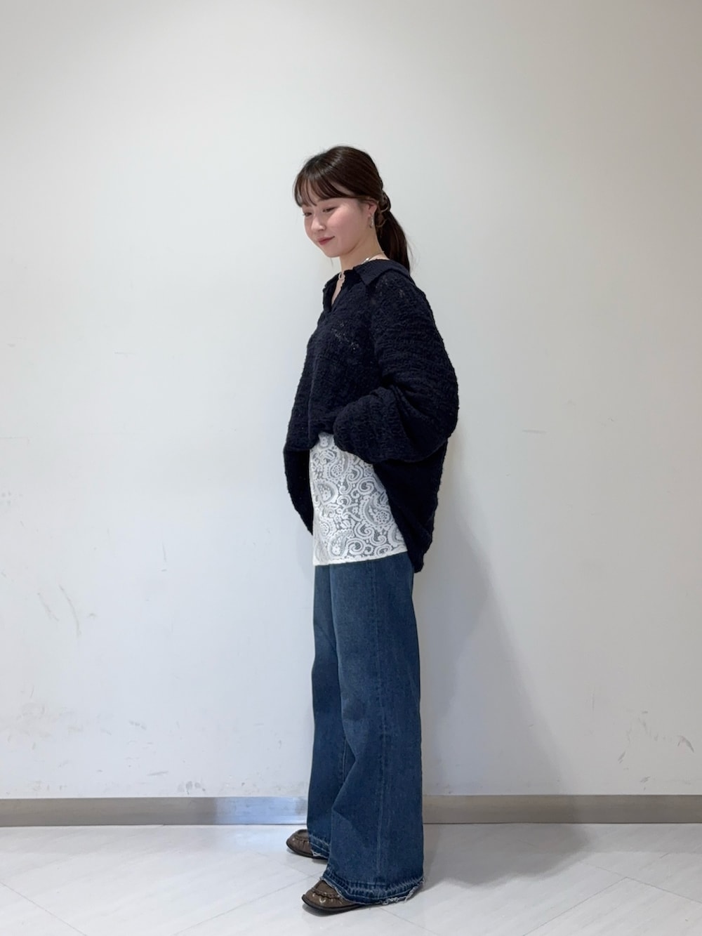ブルー系のデニムパンツ、ブラウン系のローファー、ホワイト系のショルダーバッグを着用したレディースの秋コーディネートの2枚目の写真
