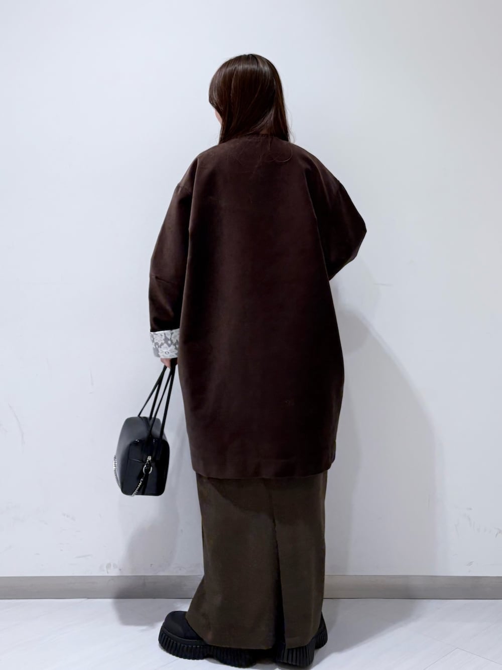 ブラウン系のその他アウター、ホワイト系のニット/セーター、ブラウン系のスカートを着用したレディースの冬コーディネートの3枚目の写真