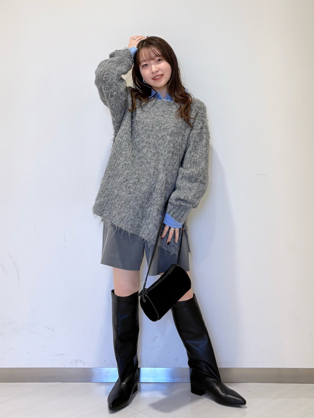 ブルー系のシャツ/ブラウス、グレー系のニット/セーター、ブラック系のショルダーバッグを着用したレディースの冬コーディネートの2枚目の写真