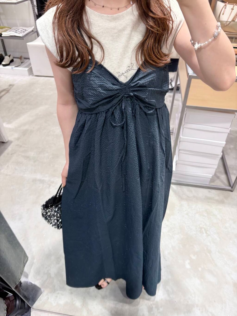 シルバー系のショルダーバッグ、ブルー系のワンピース、ベージュ系のTシャツ/カットソーを着用したレディースの夏コーディネートの3枚目の写真