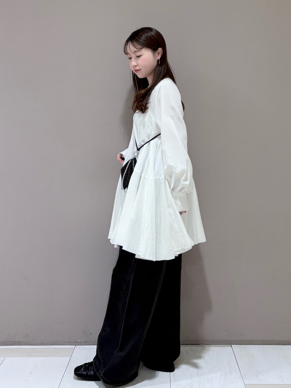 ホワイト系のワンピース、ブラック系のその他シューズ、ブラック系のデニムパンツを着用したレディースの冬コーディネートの2枚目の写真