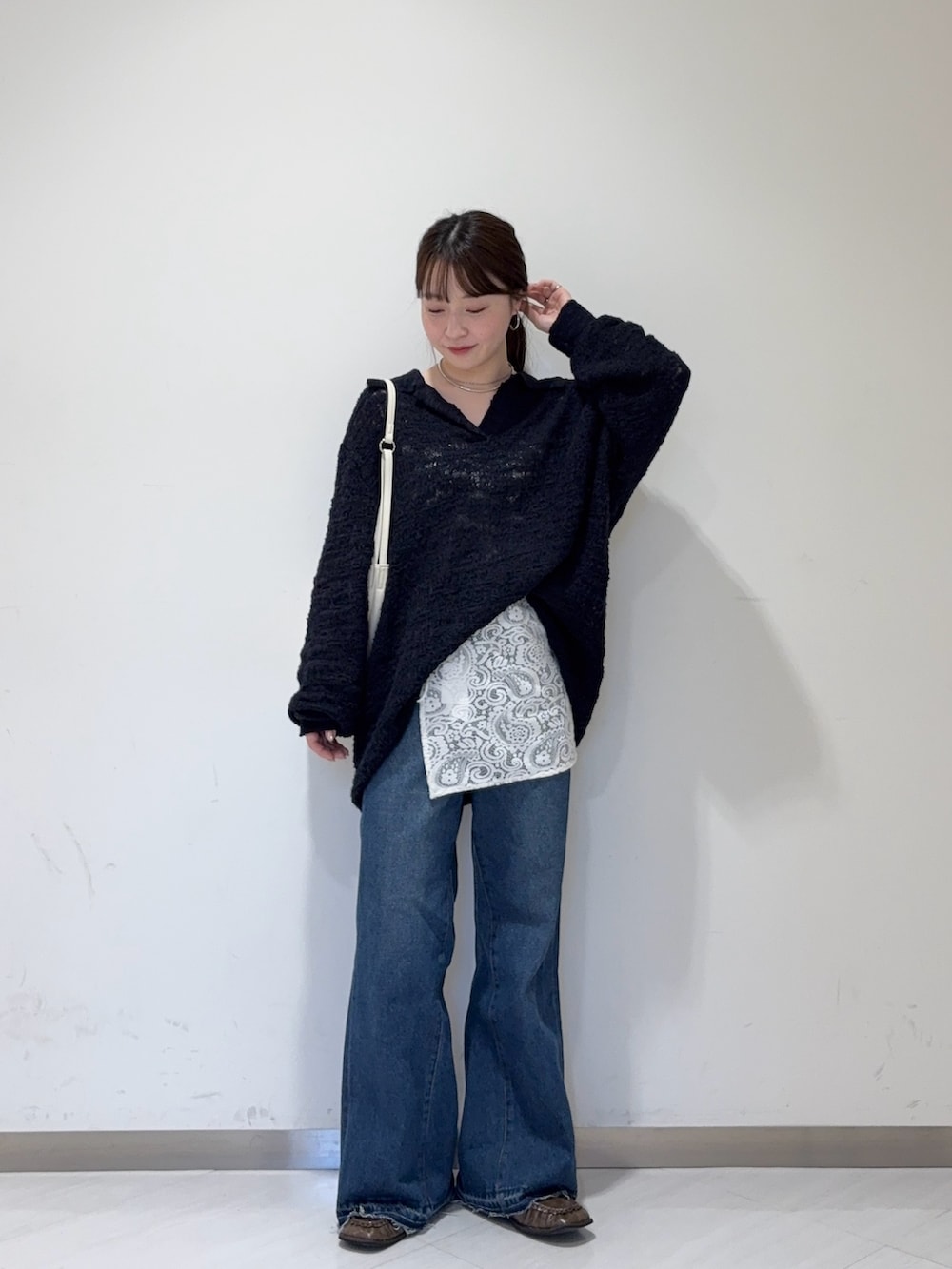 ブルー系のデニムパンツ、ブラウン系のローファー、ホワイト系のショルダーバッグを着用したレディースの秋コーディネートの4枚目の写真