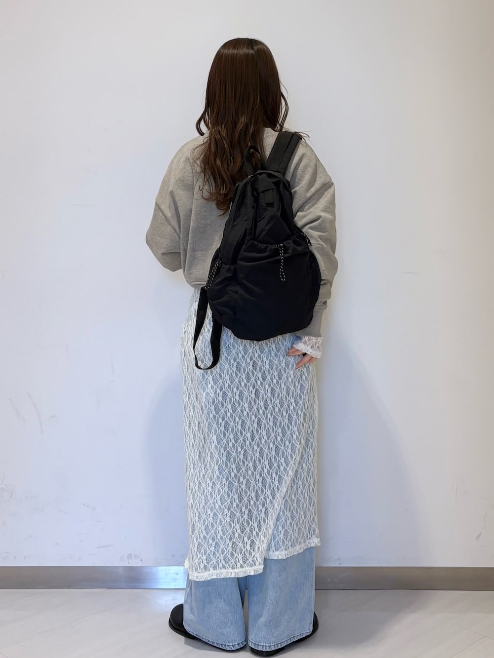 ベージュ系のスウェット、ブラック系のショルダーバッグ、ブルー系のデニムパンツを着用したレディースの春コーディネートの2枚目の写真