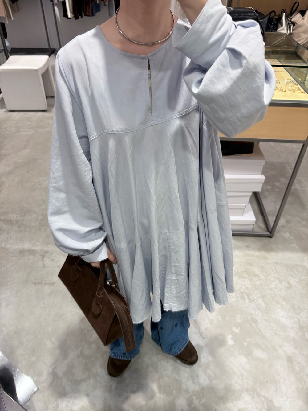 ブルー系のワンピース、ブラウン系のボストンバッグ、ブルー系のデニムパンツを着用したレディースの冬コーディネートの5枚目の写真