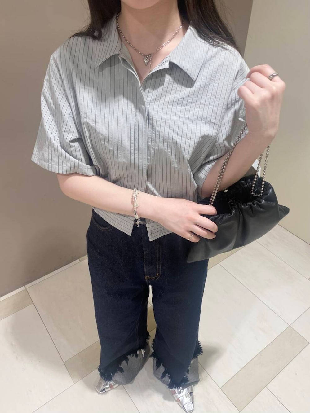 ブラック系のハンドバッグ、シルバー系のサンダル、ブルー系のデニムパンツを着用したレディースの春コーディネートの4枚目の写真