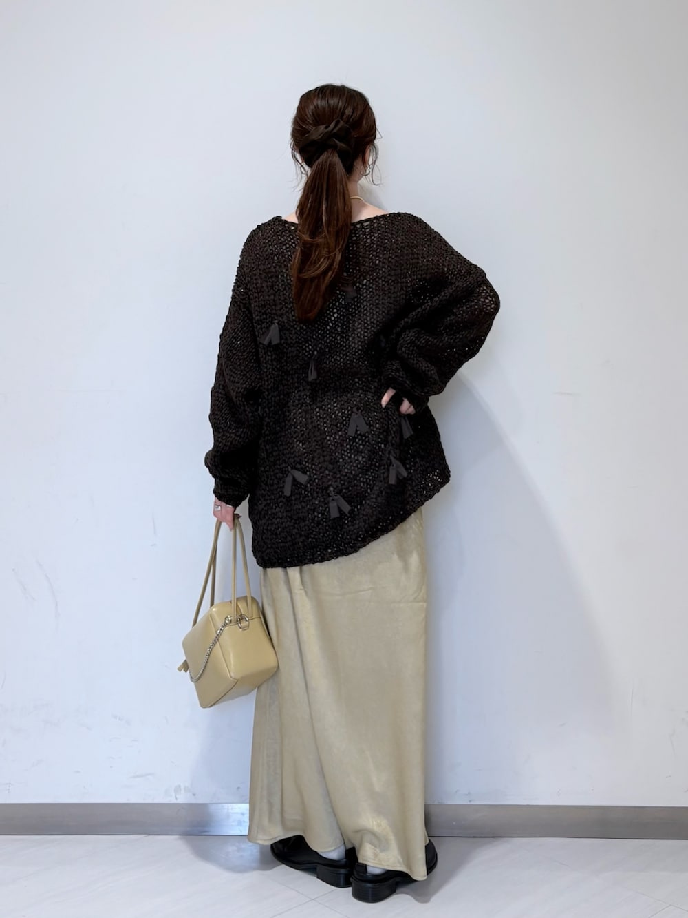 ベージュ系のスカート、ブラウン系のニット/セーター、ベージュ系のショルダーバッグを着用したレディースの冬コーディネートの3枚目の写真