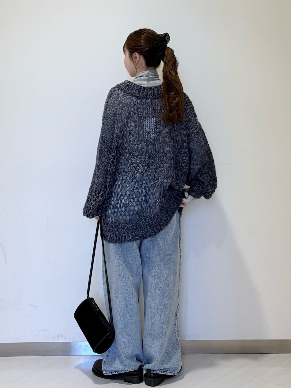 ブルー系のニット/セーター、グレー系のTシャツ/カットソー、ブルー系のデニムパンツを着用したレディースの秋コーディネートの3枚目の写真