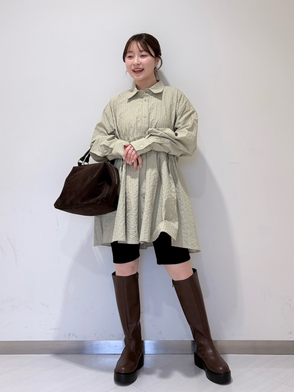 グリーン系のワンピース、ブラウン系のブーツ、ブラック系のその他パンツを着用したレディースの冬コーディネートの4枚目の写真