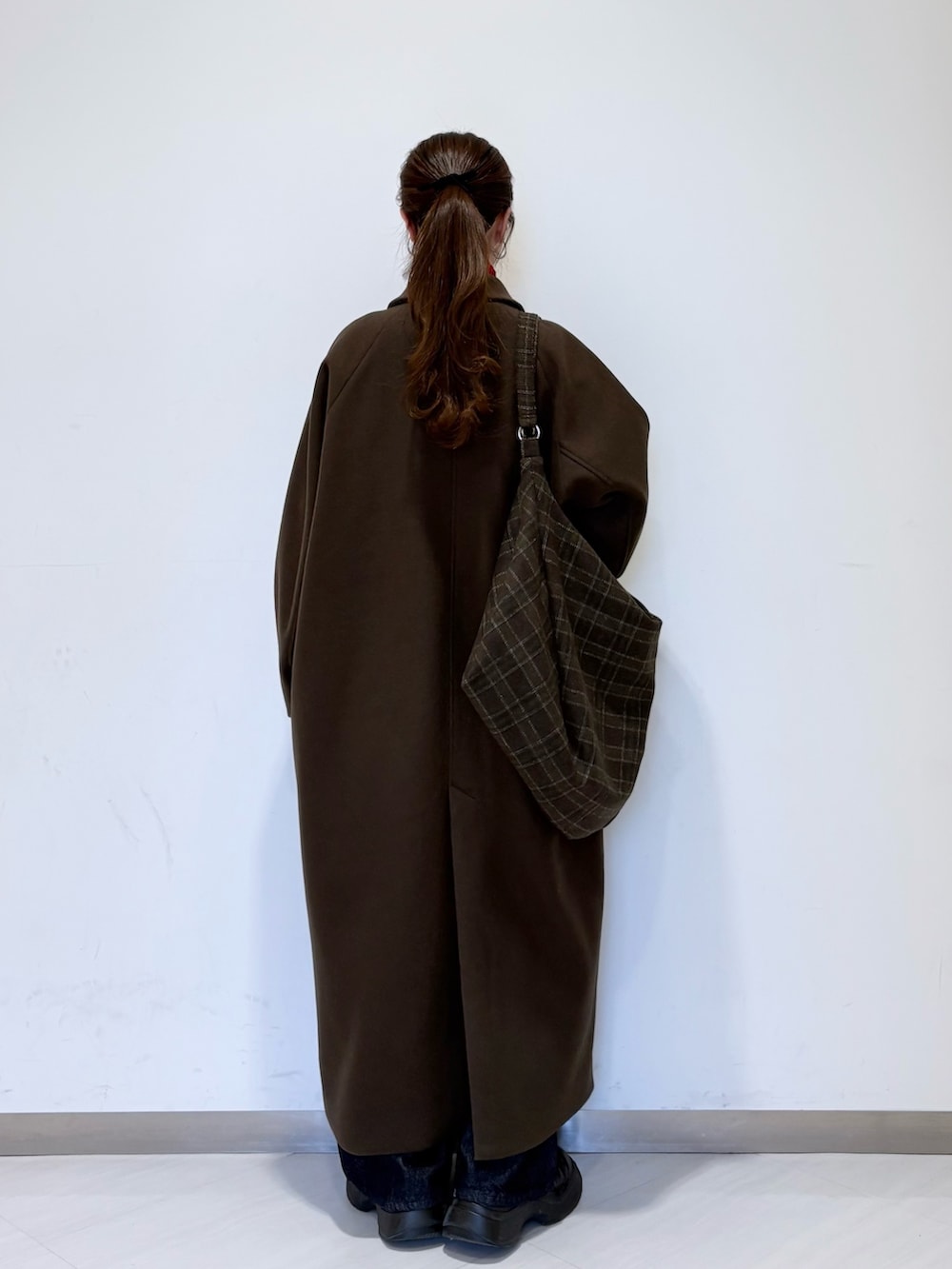 レッド系のニット/セーター、ブラウン系のステンカラーコート、ブルー系のデニムパンツを着用したレディースの冬コーディネートの3枚目の写真