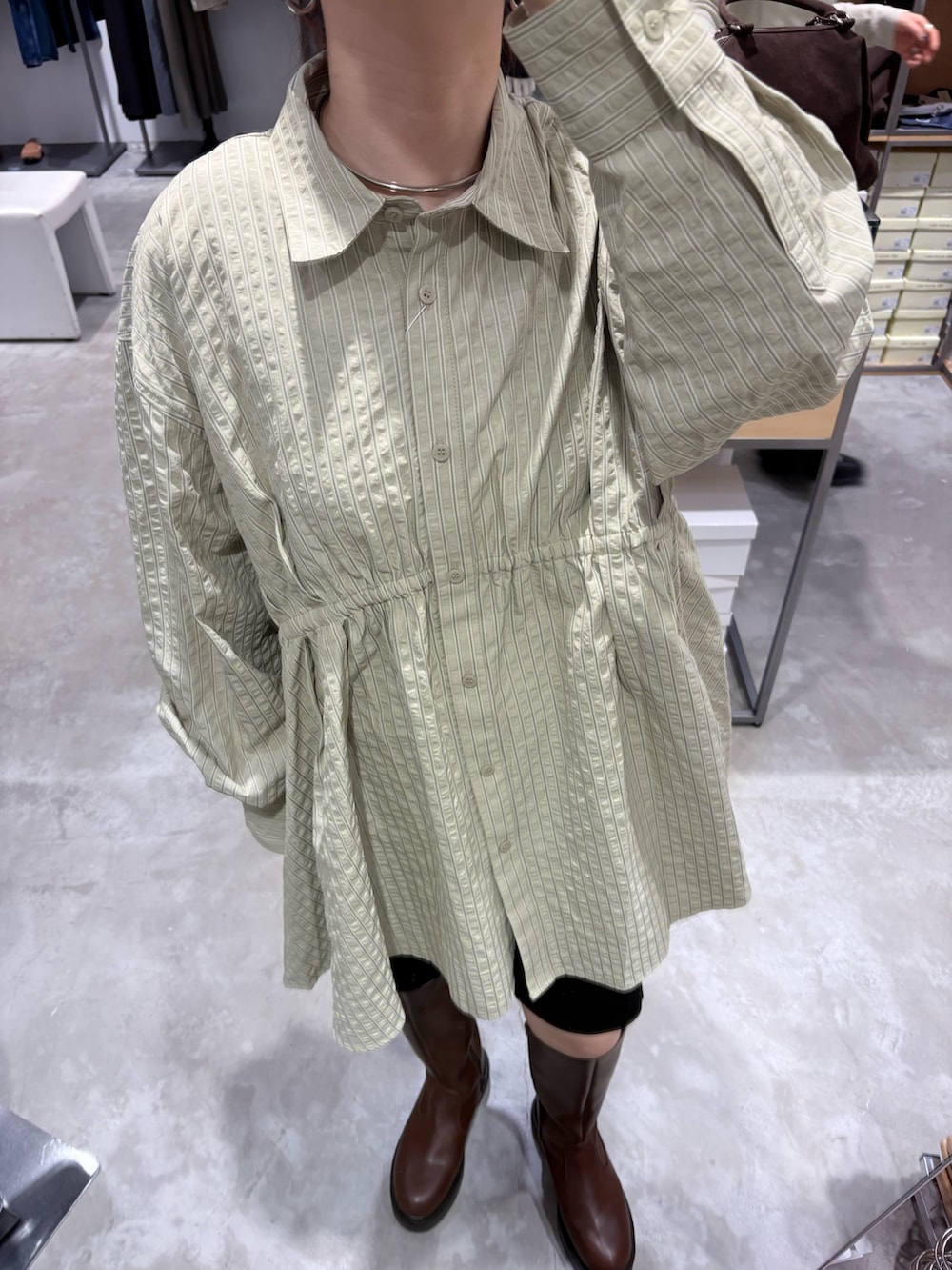 グリーン系のワンピース、ブラウン系のブーツ、ブラック系のその他パンツを着用したレディースの冬コーディネートの5枚目の写真