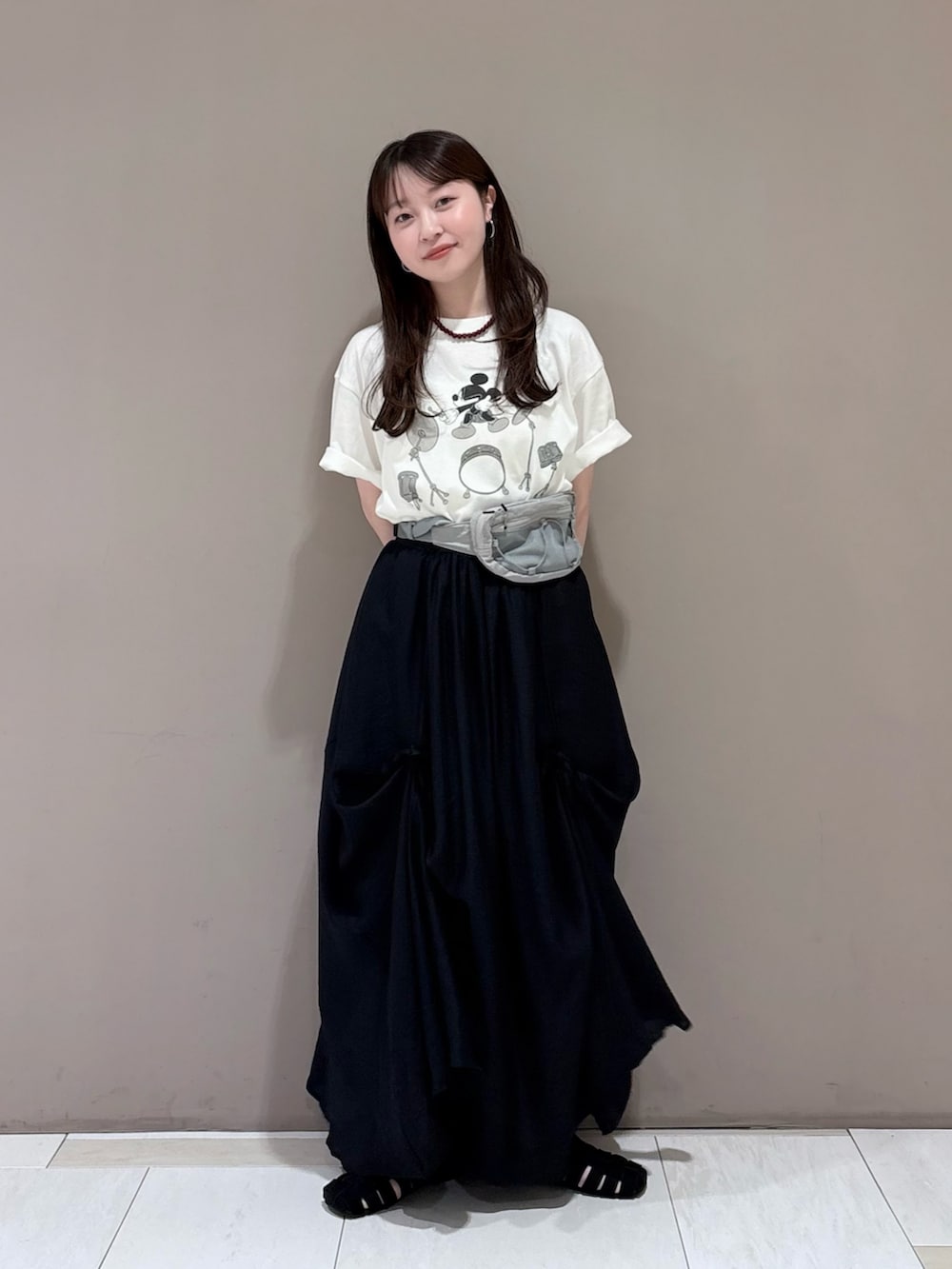 ホワイト系のTシャツ/カットソー、ブラック系のスカート、グレー系のボディバッグ/ウエストポーチを着用したレディースの春コーディネートの2枚目の写真