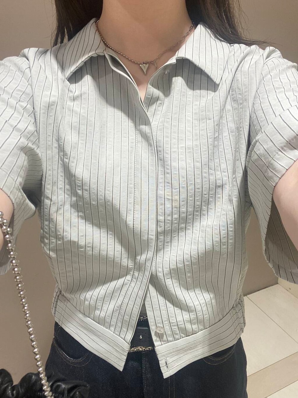 ブラック系のハンドバッグ、シルバー系のサンダル、ブルー系のデニムパンツを着用したレディースの春コーディネートの3枚目の写真