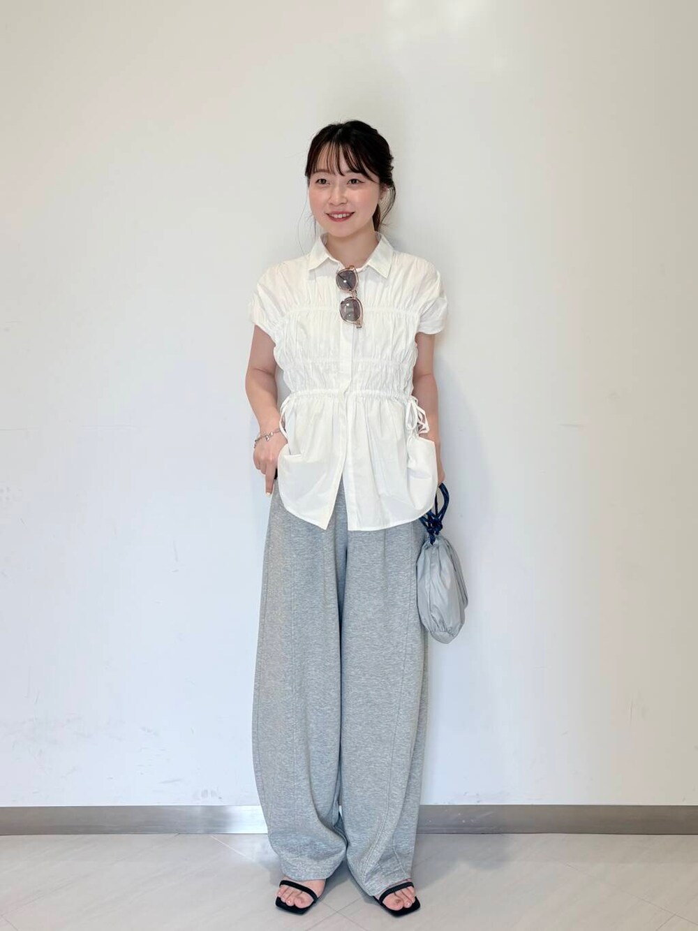 グレー系のその他パンツ、ブルー系のサンダル、ホワイト系のシャツ/ブラウスを着用したレディースの夏コーディネートの2枚目の写真