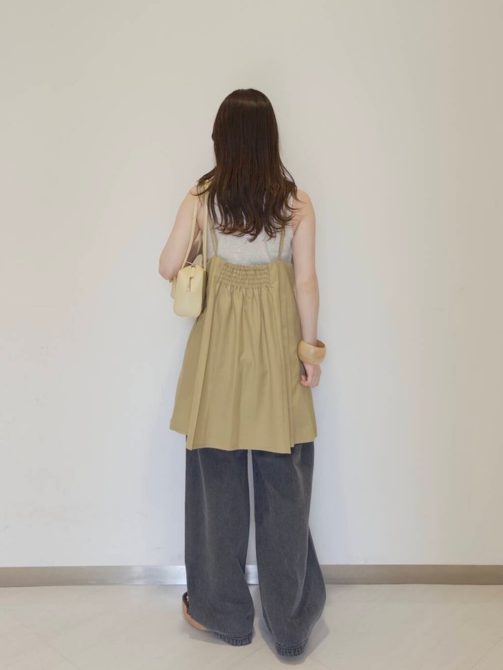 ベージュ系のタンクトップ、イエロー系のショルダーバッグ、ブラック系のデニムパンツを着用したレディースの夏コーディネートの2枚目の写真