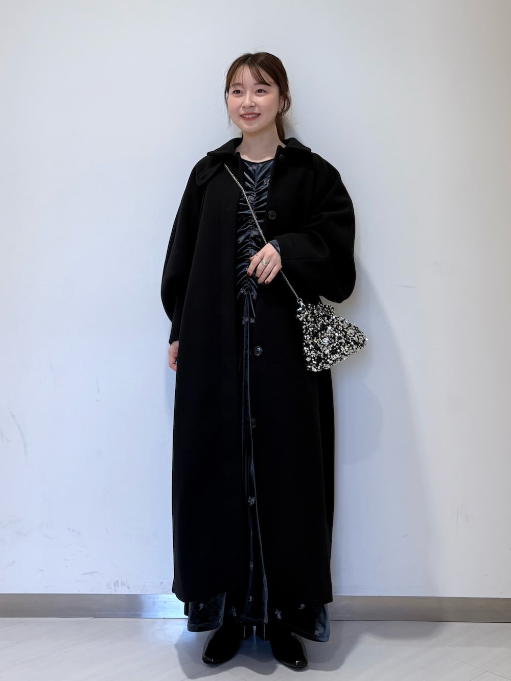 グレー系のワンピース、ブラック系のステンカラーコート、ブラック系のパンプスを着用したレディースの冬コーディネートの4枚目の写真