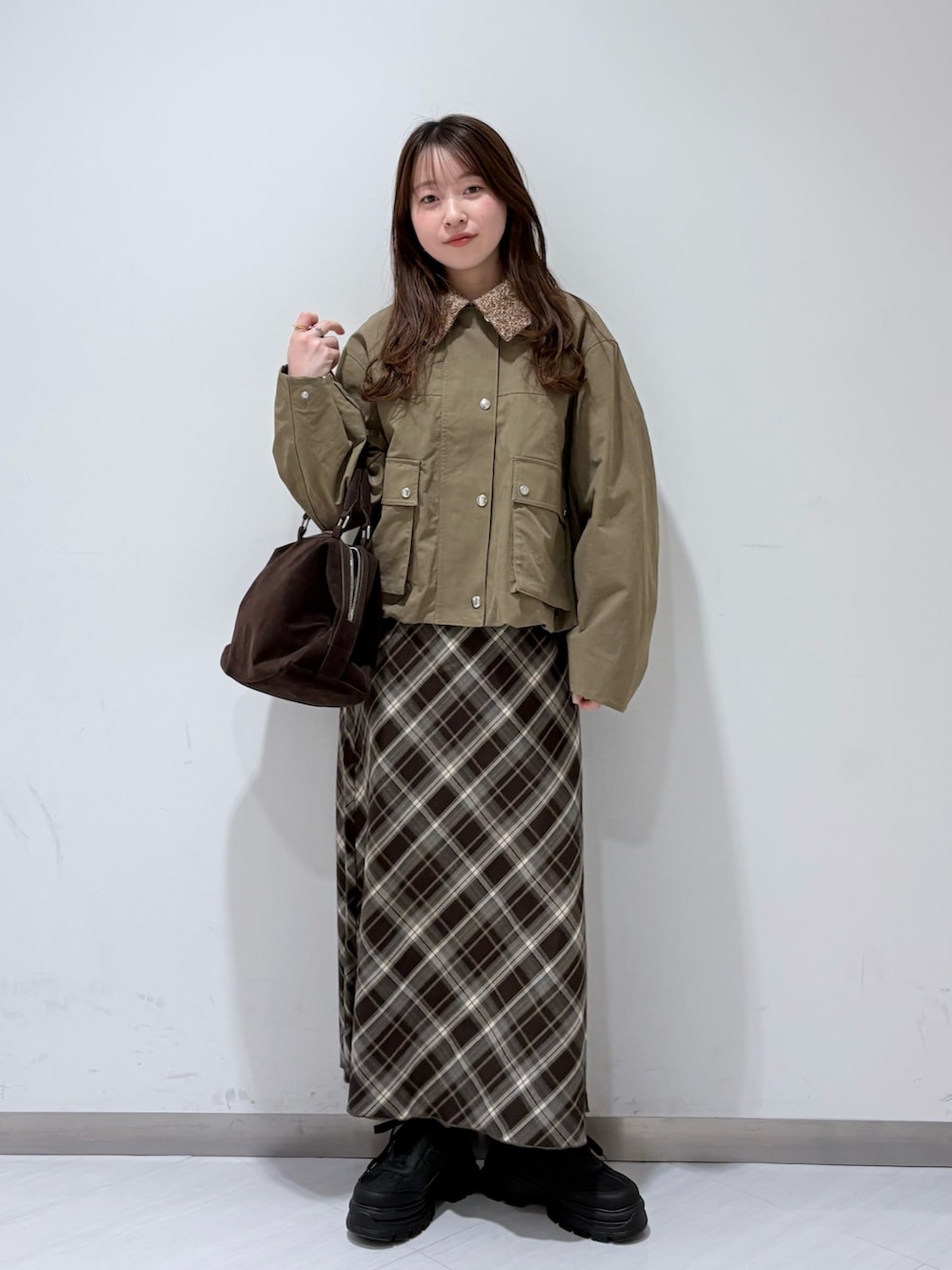 グリーン系のブルゾン、ブラウン系のスカート、ブラック系のスニーカーを着用したレディースの冬コーディネートの3枚目の写真