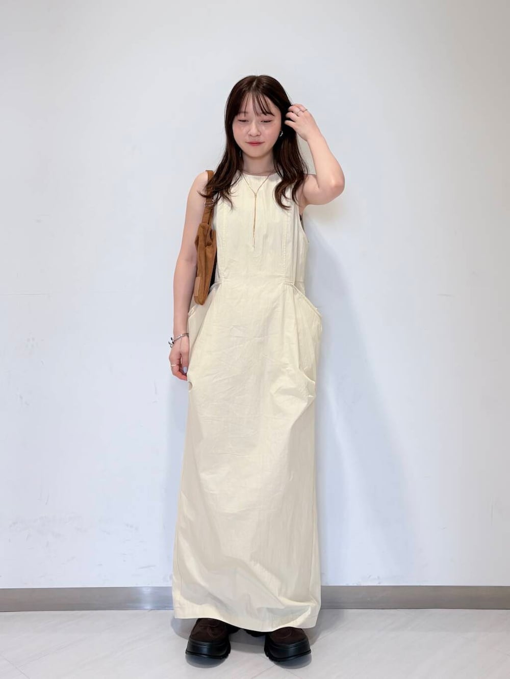 ブラウン系のスニーカー、ブラウン系のハンドバッグ、ホワイト系のワンピースを着用したレディースの夏コーディネートの2枚目の写真