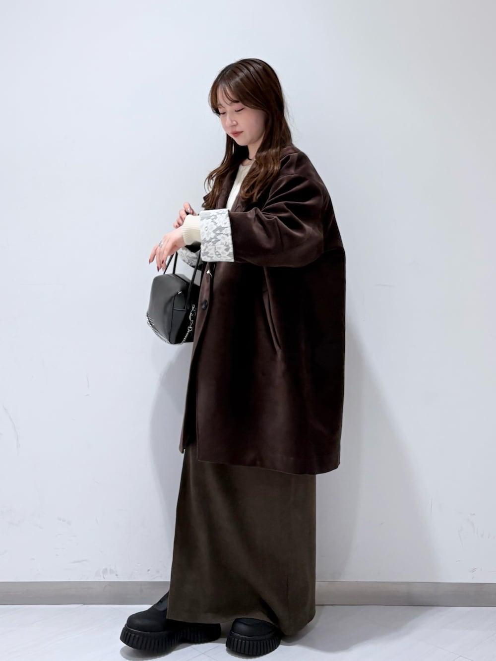 ブラウン系のその他アウター、ホワイト系のニット/セーター、ブラウン系のスカートを着用したレディースの冬コーディネートの2枚目の写真