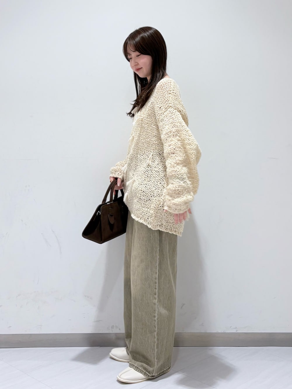 ホワイト系のパンプス、グリーン系のデニムパンツ、ブラウン系のボストンバッグを着用したレディースの冬コーディネートの2枚目の写真