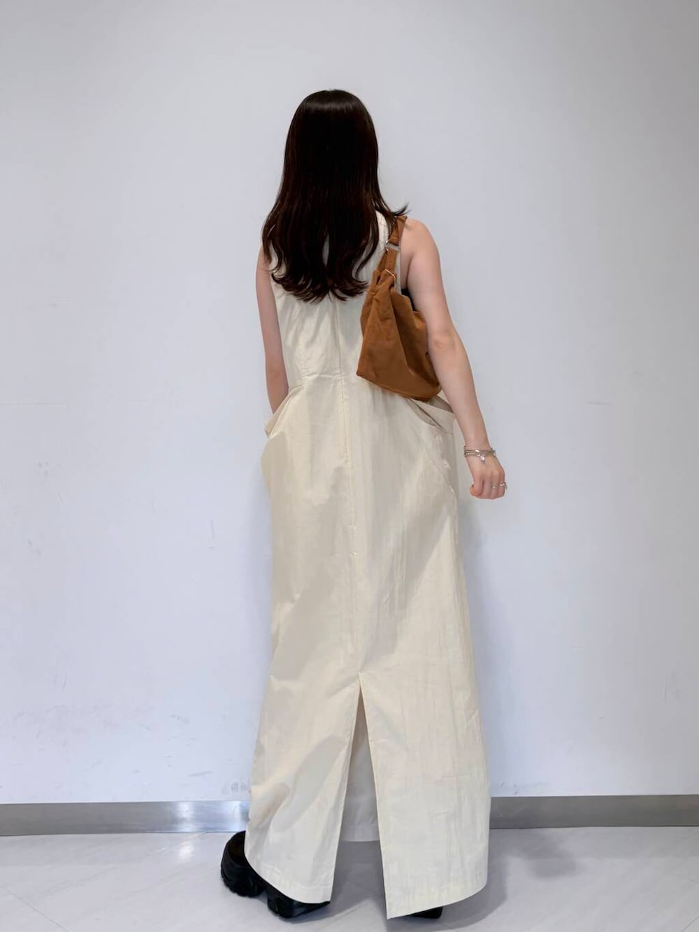 ブラウン系のスニーカー、ブラウン系のハンドバッグ、ホワイト系のワンピースを着用したレディースの夏コーディネートの3枚目の写真