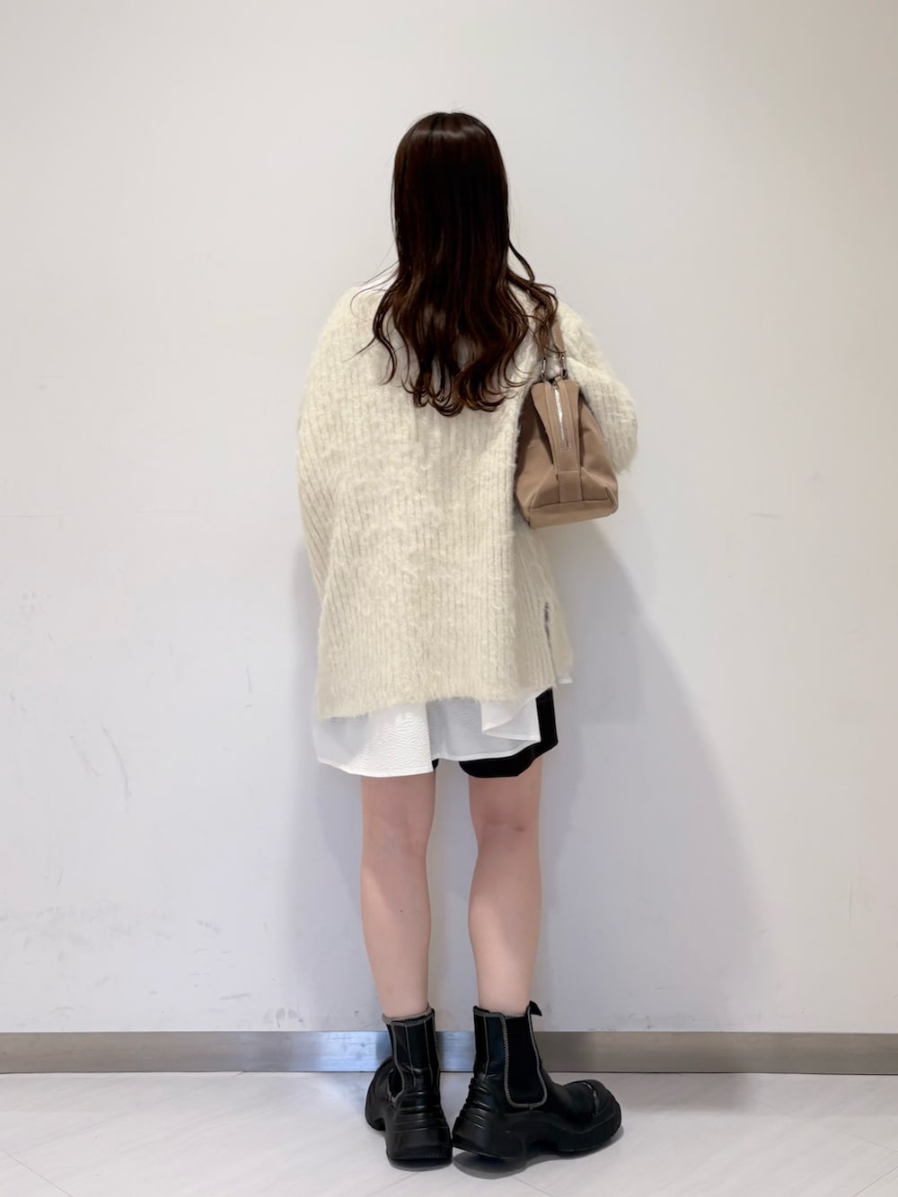 ホワイト系のニット/セーター、ベージュ系のボストンバッグ、ホワイト系のシャツ/ブラウスを着用したレディースの冬コーディネートの3枚目の写真