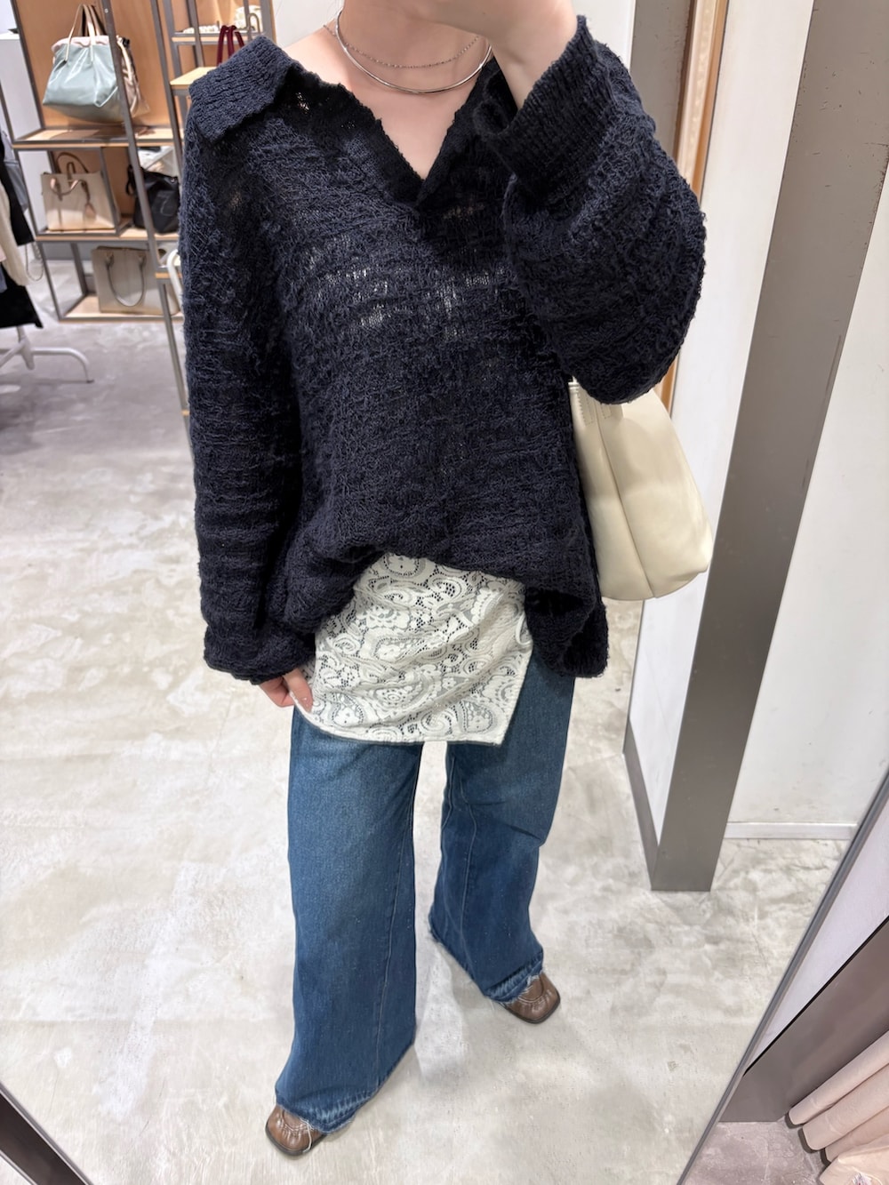 ブルー系のデニムパンツ、ブラウン系のローファー、ホワイト系のショルダーバッグを着用したレディースの秋コーディネートの5枚目の写真