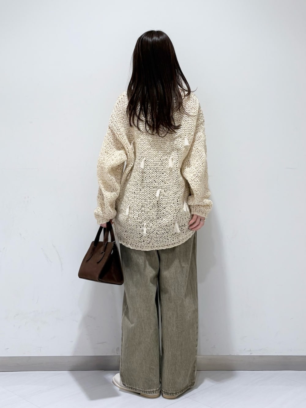 ホワイト系のパンプス、グリーン系のデニムパンツ、ブラウン系のボストンバッグを着用したレディースの冬コーディネートの3枚目の写真