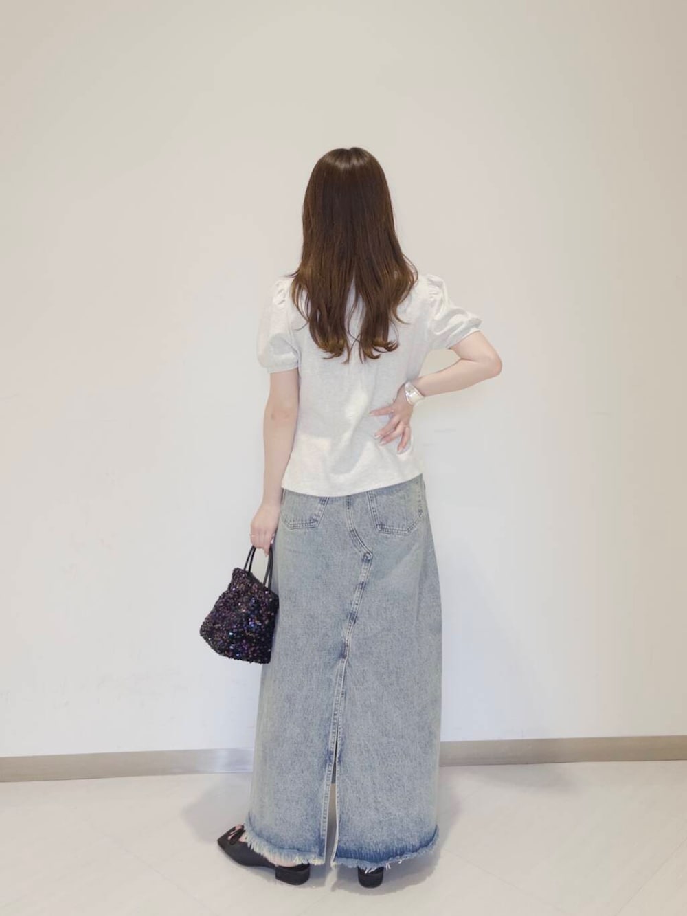 ブラック系のショルダーバッグ、ブラック系のサンダル、ブルー系のスカートを着用したレディースの春コーディネートの3枚目の写真