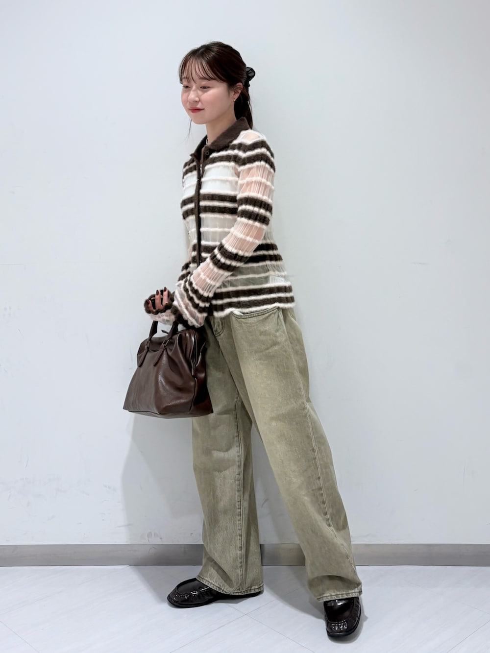 ブラウン系のニット/セーター、グリーン系のデニムパンツ、ブラウン系のボストンバッグを着用したレディースの秋コーディネートの2枚目の写真