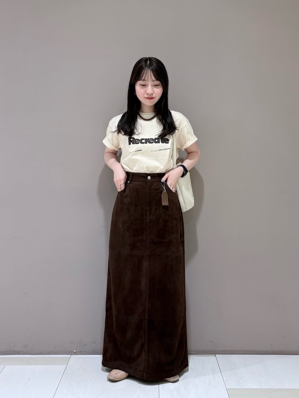 ブラウン系のスカート、ホワイト系のショルダーバッグ、ホワイト系のTシャツ/カットソーを着用したレディースの夏コーディネートの2枚目の写真