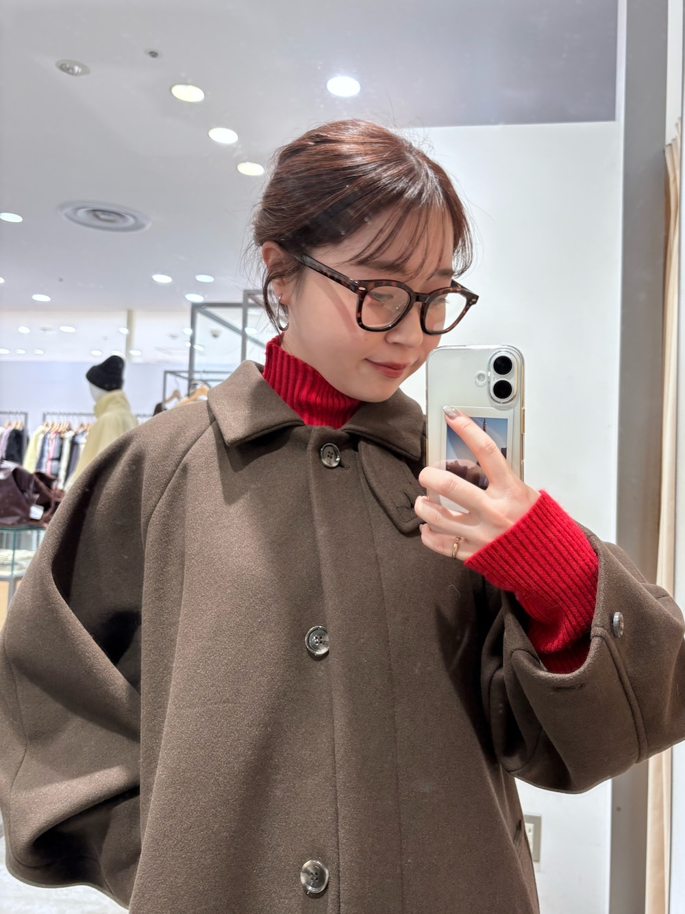 レッド系のニット/セーター、ブラウン系のステンカラーコート、ブルー系のデニムパンツを着用したレディースの秋コーディネートの4枚目の写真