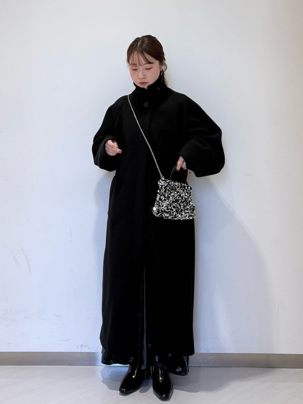 グレー系のワンピース、ブラック系のステンカラーコート、ブラック系のパンプスを着用したレディースの冬コーディネートの7枚目の写真