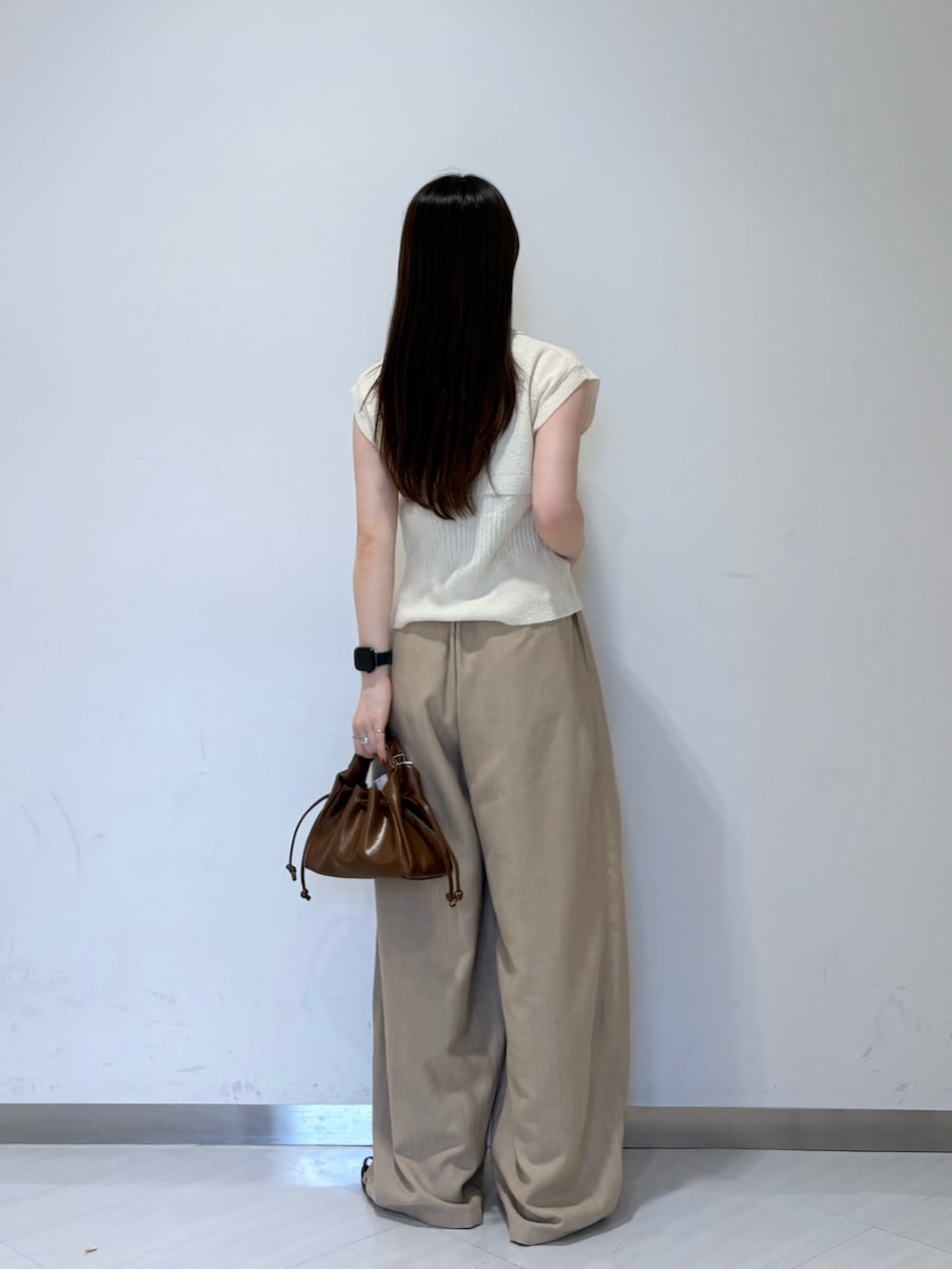 ホワイト系のニット/セーター、ベージュ系のその他パンツ、ブラウン系のハンドバッグを着用したレディースの夏コーディネートの4枚目の写真