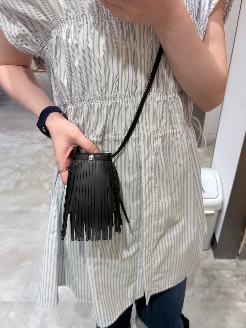 ホワイト系のワンピース、ブルー系のデニムパンツ、ブラック系のサンダルを着用したレディースの夏コーディネートの4枚目の写真